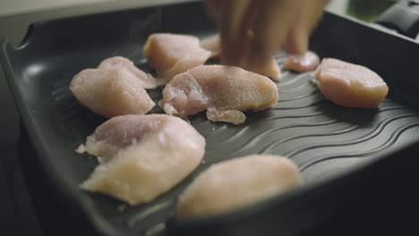 Raw-pieces-of-chicken-fillet-are-placed-in-a-hot-pan-and-fried