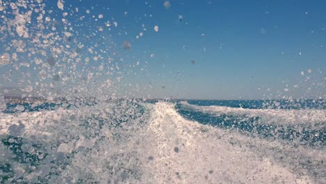 Low-angle-perspective-of-motor-boat-wake-trail-and-water-spray-on-sea-surface