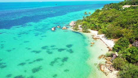 Parasailing-over-beautiful-tranquil-lagoon-with-coral-reefs-underwater,-exotic-beach-with-white-sand-bordered-by-tropical-plants-and-turquoise-sea,-ko-Phangan,-Thailand