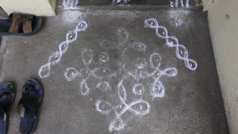 Worn-out-rangoli-in-front-of-a-household-front-door-with-shoes-on-the-side