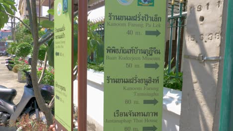 Signboard-with-directions-to-tourist-attractions-in-Bangkok-written-in-Thai-and-English