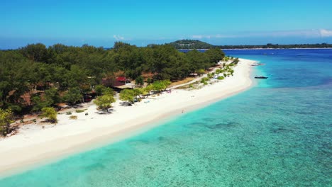 Paradise-quiet-exotic-beach-with-white-sand-washed-by-calm-clear-water-of-turquoise-lagoon-of-tropical-island-with-lush-vegetation-in-Indonesia