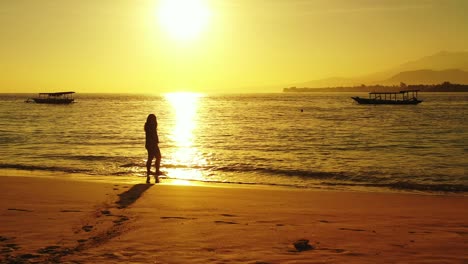 Fiji-Island-Resort-Showing-A-Young-Lady-Standing-By-The-Shore-Bathing-Her-Barefoot-With-The-Seawater-Under-A-Beautiful-Morning-Sunrise---Wide-Shot