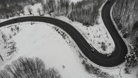 Aerial,-drone-shot,-panning-around-cars-on-a-wet,-winding-road,-in-the-mountains,-bad-conditions,-on-a-cloudy,-winter-day,-in-Romania