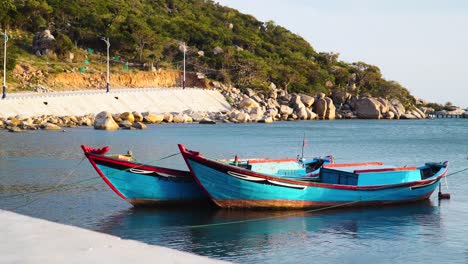 Small-boats-painted-vivid-blue-in-quiet-haven,-Vinh-Hy-Bay,-Vietnam