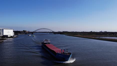 Wilson-Waal-Barge-Sailing-Across-Noord-River-With-Bridge-In-The-Background-At-Hendrik-Ido-Ambacht,-Netherlands