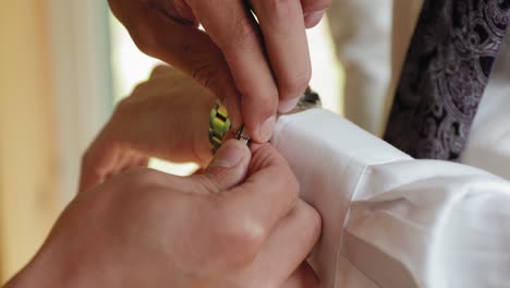 Groomsman-assists-a-groom-to-put-on-a-bracelet-and-watch-while-getting-ready-for-his-wedding