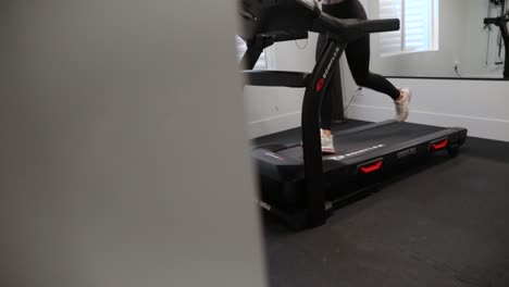 Female-Woman-Exercising-by-Running-on-Treadmill-at-Indoor-Home-Gym,-Reveal