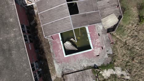 Top-Down-Aerial-Drone-Footage-Rising-and-Turning-over-an-Abandoned-Covered-Pool-and-Hotel