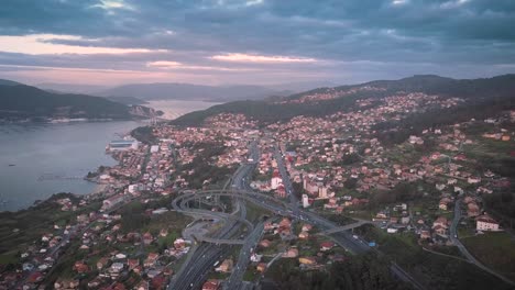 Luftaufnahme-Der-Autobahn-AP9-Bei-Farbenprächtigem-Sonnenuntergang-Im-Abendverkehr-Und-Der-Hängebrücke-über-Den-Atlantischen-Ozean-In-Vigo,-Spanien