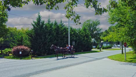 An-Amish-Open-Horse-and-Buggy-With-Four-Amish-Teenagers-in-it-Traveling-Down-a-Country-Road-on-a-Sunny-Summer-Day