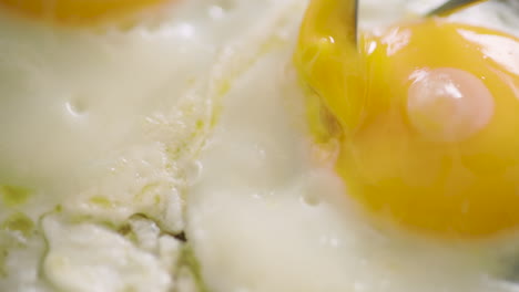 Cutting-a-fried-egg-in-pieces-and-lifting-it-up---slow-motion,-close-up-shot