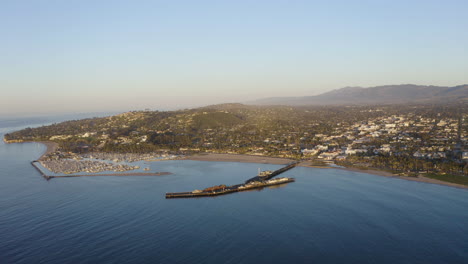 Santa-Barbara-California-drone-angle-looking-toward-harbor-town-with-pier-ocean-waves-and-boats-4k-prores