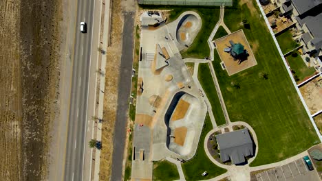 Ascending-aerial,-bird's-eye-view-of-an-urban-skate-park-in-summer