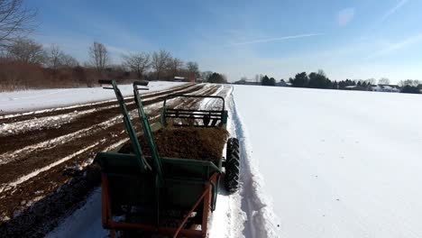 Agricultural-Machinery-Is-Being-Pulled-To-Spread-Manure-On-Farmland-During-Sunny-Winter-Day