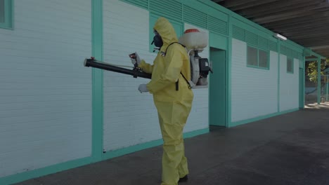 Worker-disinfects-school-exterior-area-from-coronavirus-covid-19-with-antibacterial-sanitizer-sprayer