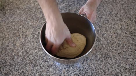 Placing-a-sourdough-ball-into-a-metal-mixing-bowl-with-some-oil,-the-dough-is-turned-in-the-oil-before-setting-aside-to-rise-before-forming-into-sourdough-bagels-and-cooking