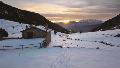 Sanfte-Drohne,-Die-Durch-Die-Verschneite-Stadt-Cortals-In-Andorra-Reist,-Im-Hintergrund-Der-Sonnenuntergang-Hinter-Den-Pyrenäen