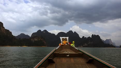 colorful-ribbons-waving-in-wind-on-longtail-boat-in-front-of-mountain-scenery