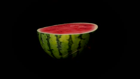 Statische-Nahaufnahme-Einer-Beleuchteten-Rotierenden-Halben-Wassermelone-Im-Studio-Mit-Schwarzem-Hintergrund