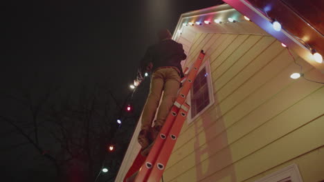 A-man-is-on-a-ladder-hanging-christmas-lights