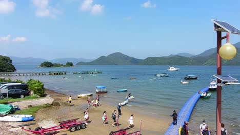 Locals-walking-on-a-small-pier-in-Hong-Kong-with-small-boats-in-the-water-on-a-summer-day