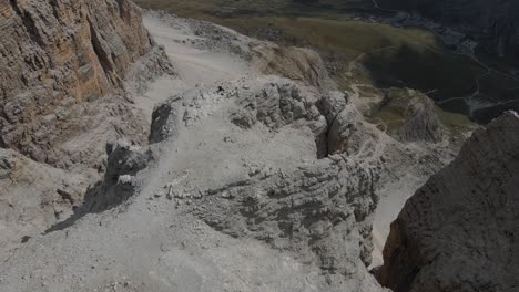 High-mountain-trail-in-Dolomites,-aerial-view-of-spectacular-rock-peak-and-abyss