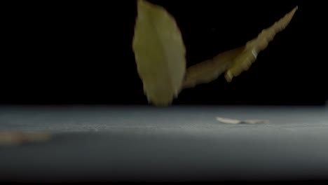 Dried-bay-leaves-fall-on-a-table-in-slow-motion
