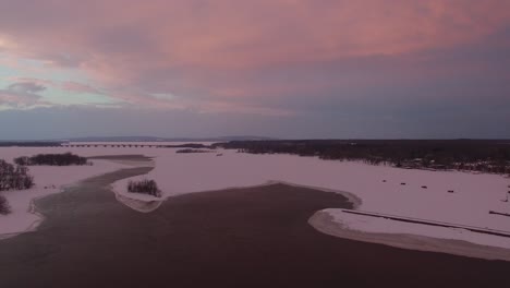 Beautiful-sunset-skies-seen-by-drone-flying-forward-over-half-frozen-lake