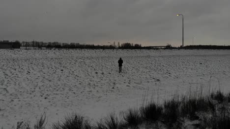 Man-Walks-Uphill-In-The-Snowy-Field-On-A-Cloudy-Day-In-Wintertime