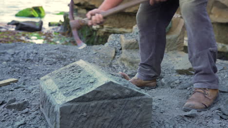 Handheld-medium-wide-shot-showing-a-stone-craftsman-carefully-chipping-at-a-block-of-stone-to-shape-it,-in-the-city-of-Ancud,-Chiloe-Island