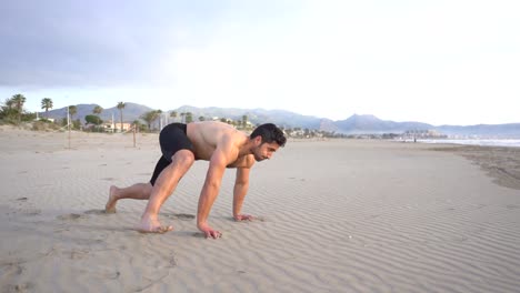 Man-doing-functional-floor-exercises-on-the-beach-sand-in-slow-motion