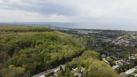 Beautiful-aerial-flight-over-natural-forest-near-Grimsby-City-and-Lake-Ontario-in-background