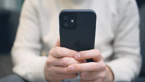 Close-up-of-back-of-new-dark-iPhone-being-used-by-white-male-hands