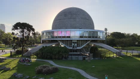 Aerial-pan-right-of-Galileo-Galilei-Planetarium-in-Palermo-Woods-at-golden-hour,-Buenos-Aires