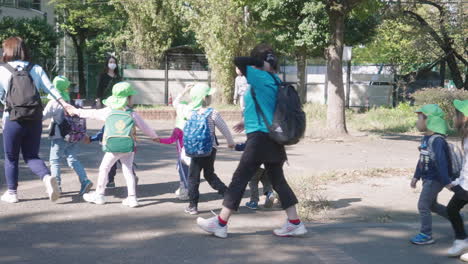 Backpacker-Japanese-Primary-School-Kids-Guided-By-Their-Teachers-During-Educational-Trip-In-Park,-Tokyo-Japan