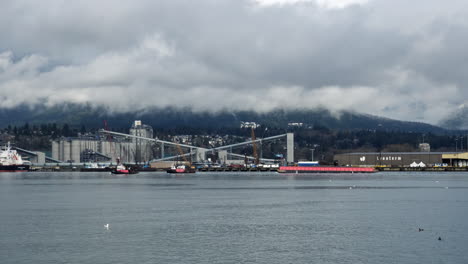 Traffic-on-Vancouver-Fjord-with-cruising-tug-boats,-vessel-ship-and-factory-in-background