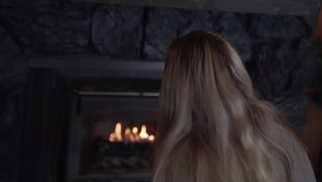 Blonde-woman-sat-looking-into-fireplace