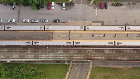 A-top-down-shot-directly-over-a-railroad-train-station-with-one-train-stopped-and-another-pulling-out-of-the-station