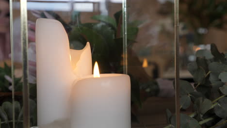 Two-Candles-Burning-In-Glass-Container-With-Gum-Leaves,-SLOW-MOTION