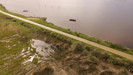 4K-aerial-view-of-the-silhouette-of-two-old-fishing-boats-anchored-in-the-middle-of-the-Ria-de-Aveiro,-estuary-of-river-Vouga,-drone-rotating-to-the-left,-60fps