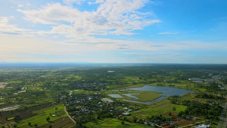 Above-aerial-view-moving-and-seeing-swamp-countryside-with-the-road-a-sunny-day-in-Khonkaen,-Thailand