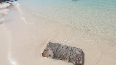 Rusty-metal-barrel-buried-in-the-sand-of-Koh-Hey-contrasting-with-the-clear-paradisiac-waters---Wide-Tracking-shot