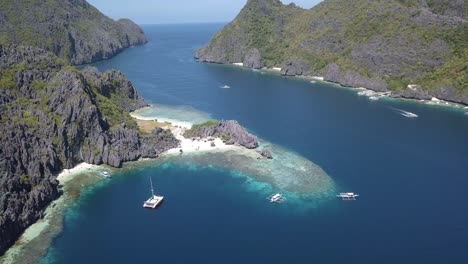 4K-Aerial-Drone-View-of-Private-Island-Star-Beach-in-Palawan-Philippines-with-Yacht-in-Bay-and-Local-Tour-Boats-of-Philippines