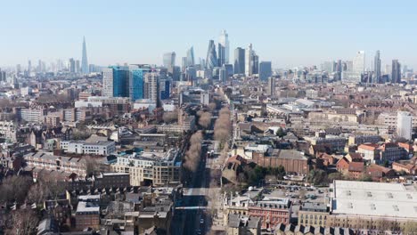 Dolly-back-drone-shot-of-city-of-London-skyscraper-cluster-over-Whitechapel-road