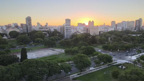 Dolly-out-of-Recoleta-neighborhood-buildings-revealing-Floralis-Generica-steel-sculpture-at-golden-hour,-Buenos-Aires
