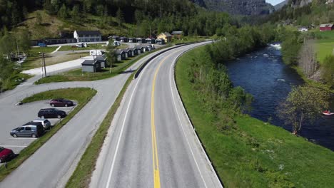 Cars-driving-on-road-E16---Tvindefossen-camping-at-Voss-in-background
