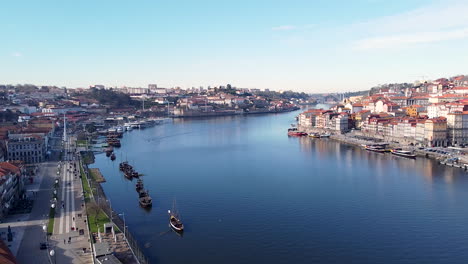 Aerial-view-of-Douro-river,-Gaia-and-Porto-river-banks-on-a-sunny-day,-drone-going-backward