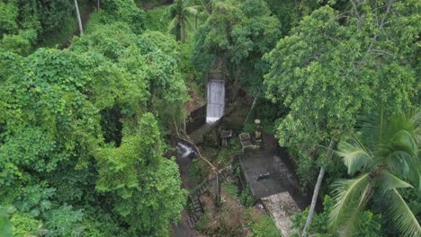 Aerial-View,-Small-Creek-Waterfall-and-Hidden-Terrace-in-Dense-Rainforest-on-Bali-Island,-Indonesia,-Tilt-Down-Drone-Shot