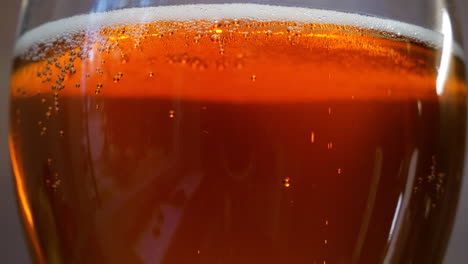 Glass-full-of-dark-beer-with-rising-bubbles,-close-up-view